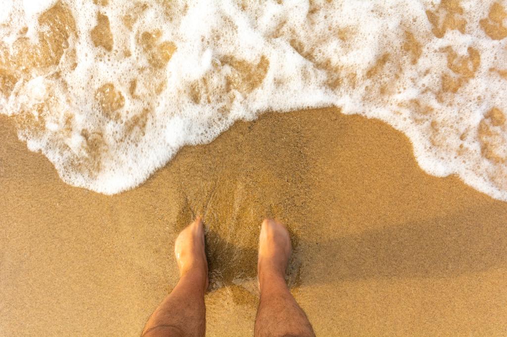 Foto ilustrasi menenggelamkan kaki di pasir pantai