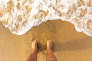 Foto ilustrasi menenggelamkan kaki di pasir pantai