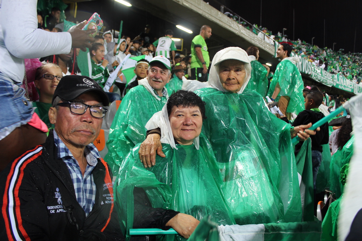 A picture of fans at the football game dressed in green waterproof ponchos.