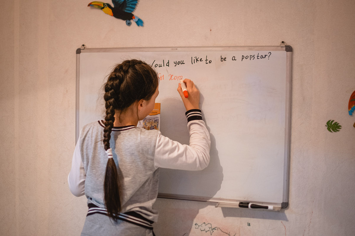 François Artusse, Udege people Russia – young girl with long braided hair writing the Russian translation for the English sentence