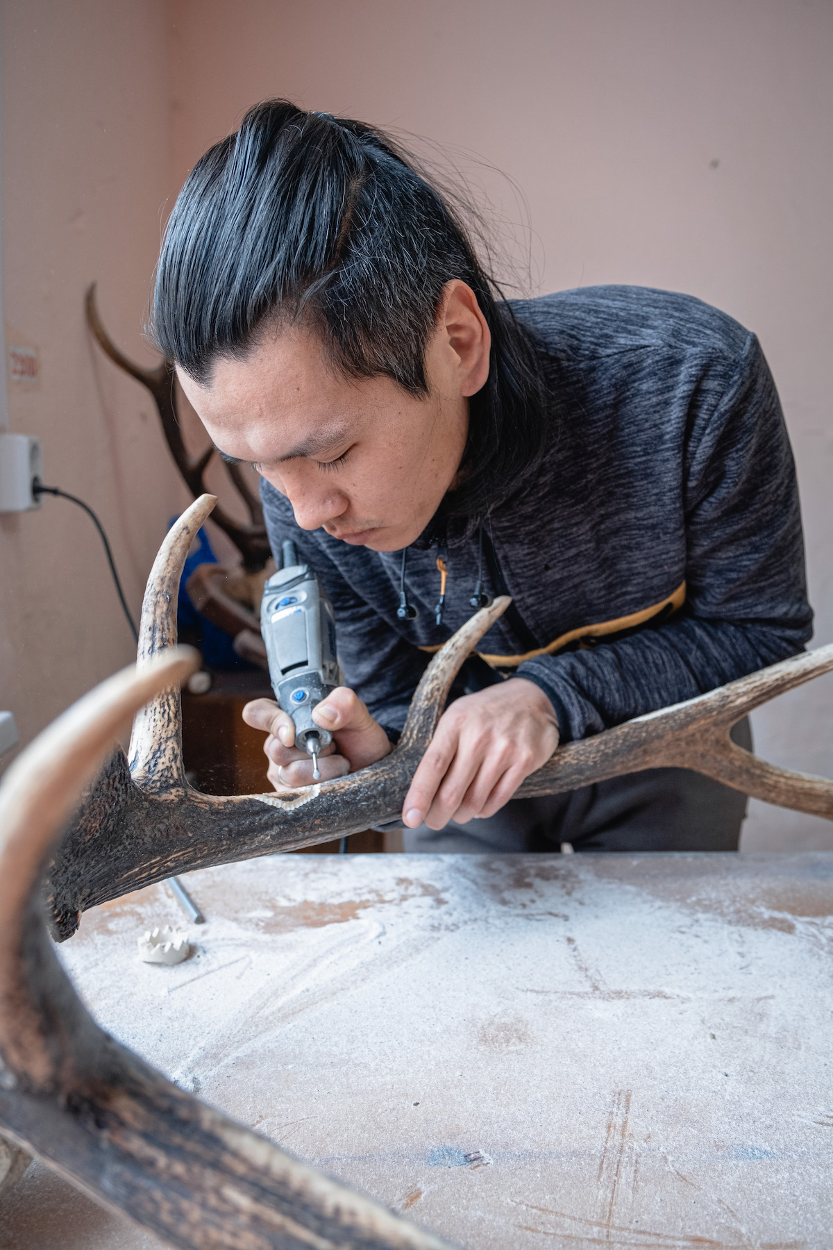 François Artusse, Udege people Russia – man carving intricate details into deer antlers with a special tool.