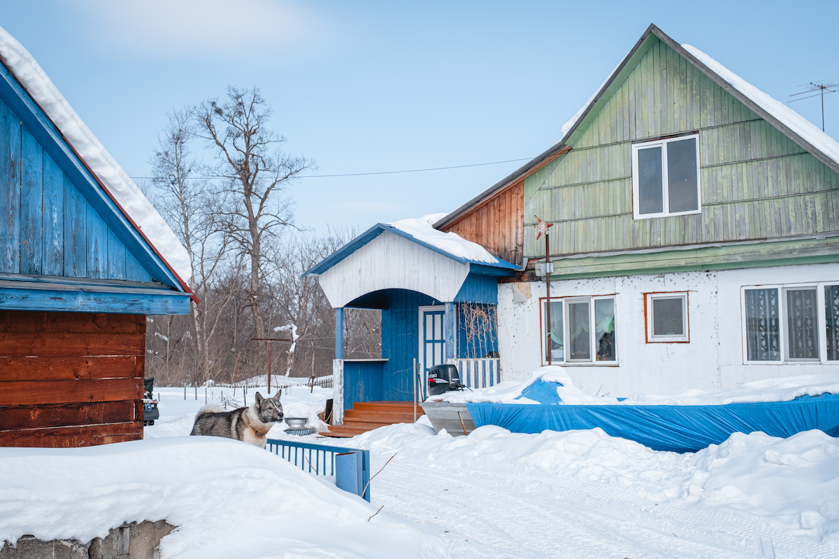 François Artusse, Udege people Russia – wooden houses with colourful details, all covered in snow.