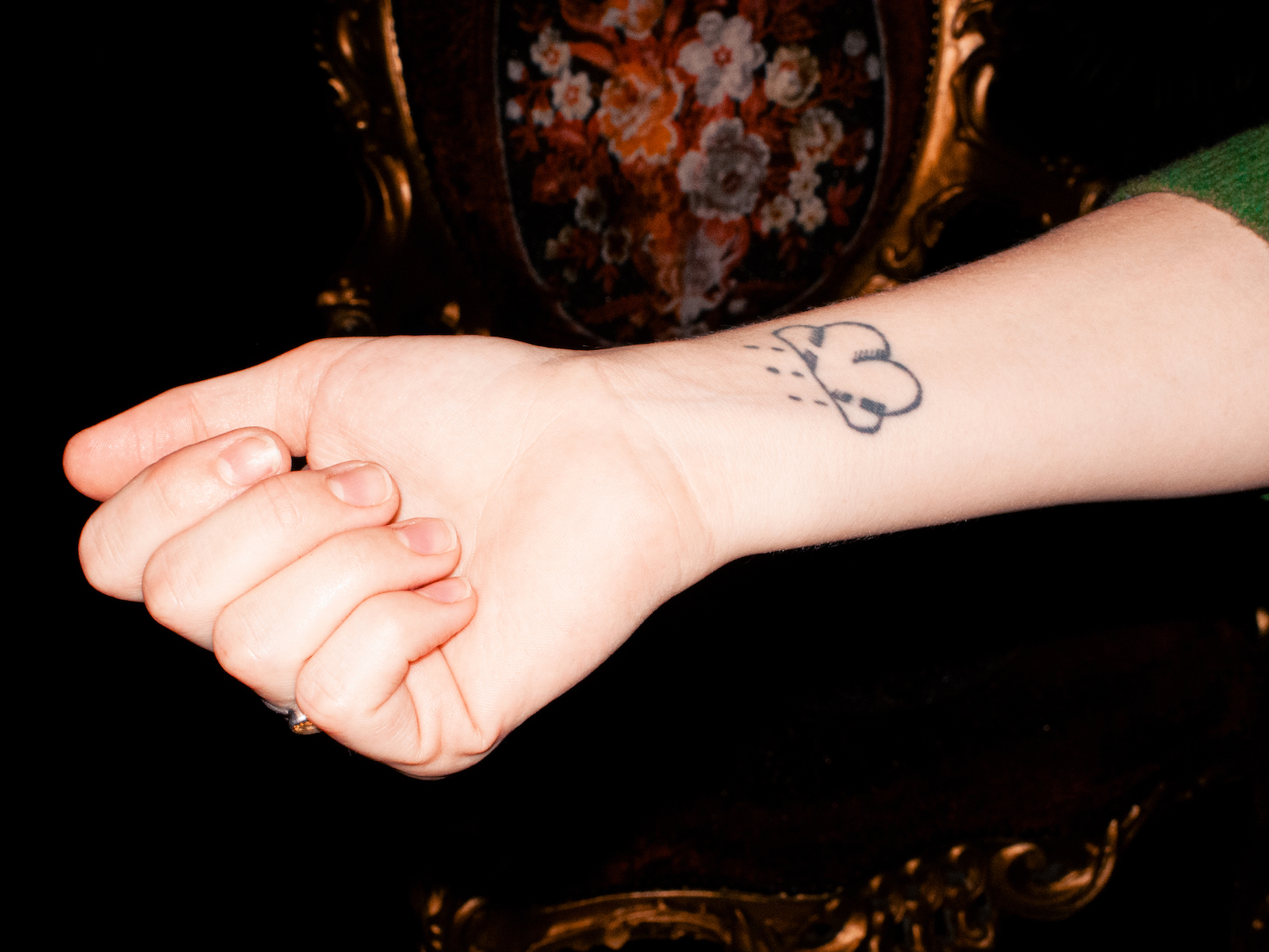 Photo of a woman's wrist featuring an amateurish tattoo of a cloud with rain falling.