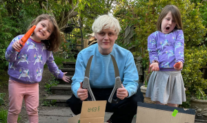 The author kneels down between his two nieces, 4 and 6, holding a range of knives and garden saws