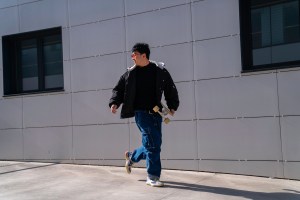 Asian man with skateboard walking fast