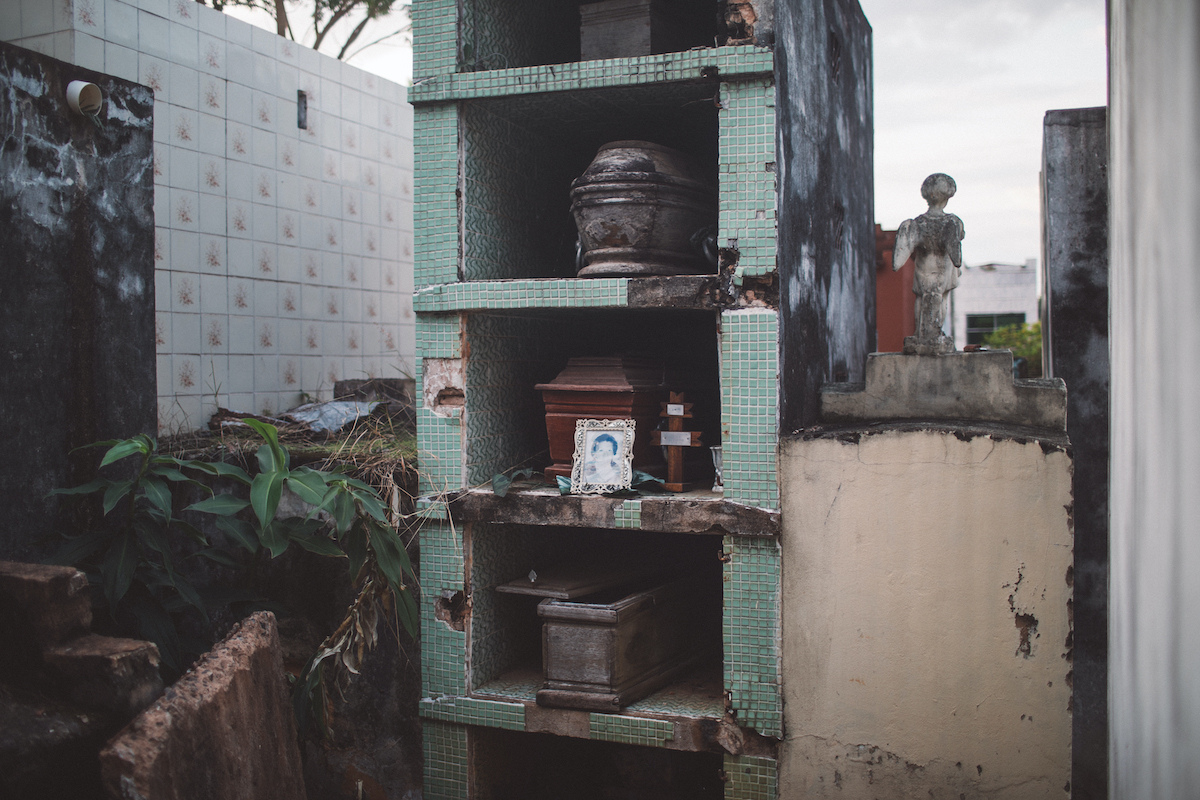 A photo of caskets stacked in vertical tombs adorned with green mosaic tiles.