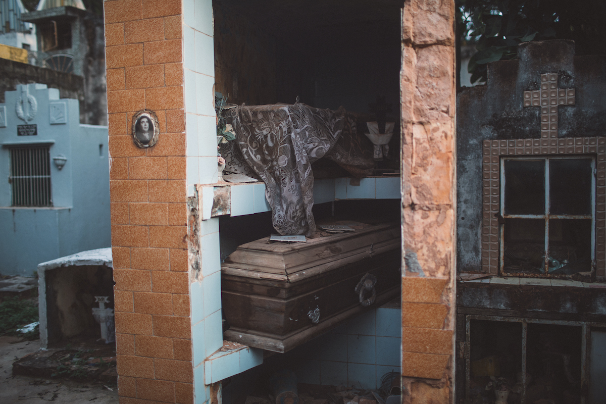 A photo of several vertical tombs, many of them open; one is adorned with orange tiles.