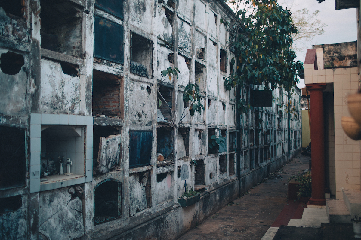 A photo of a wall of vertical tombs, about half of them are smashed open.