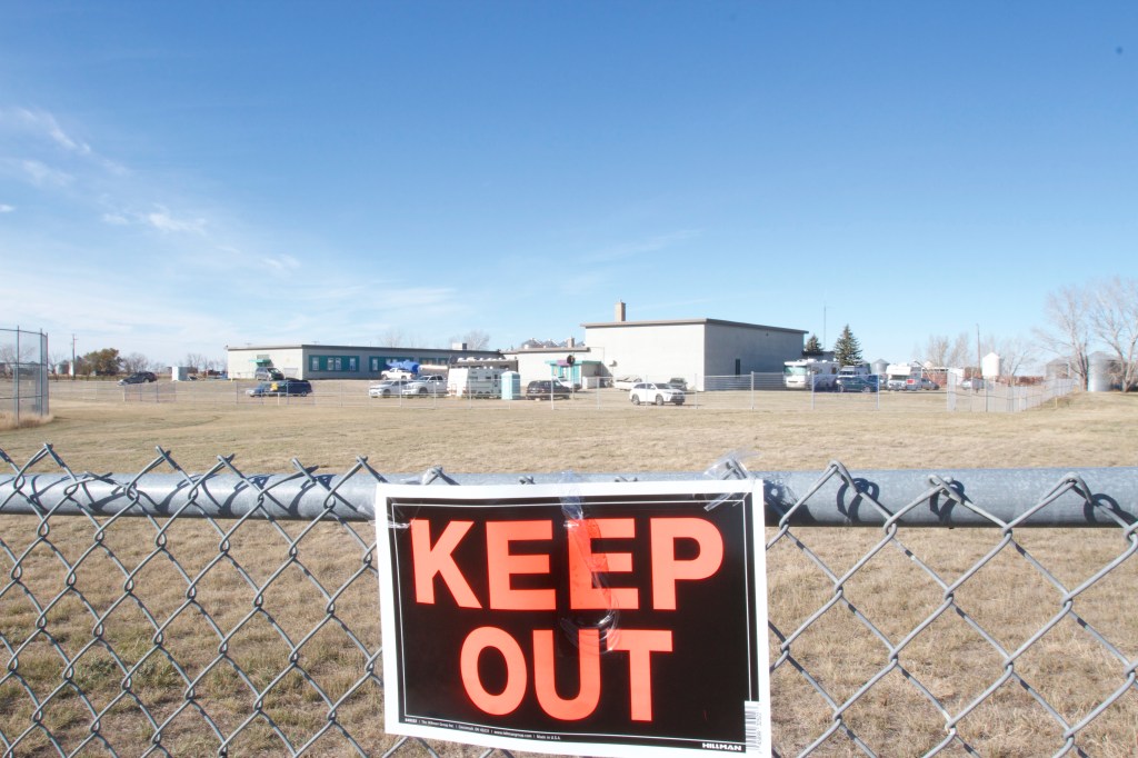 A "keep out sign can be seen on a chainlink fence outside of a school taken over by a QAnon cult. All photos by Mack Lamoureux and Evy Kwong.​