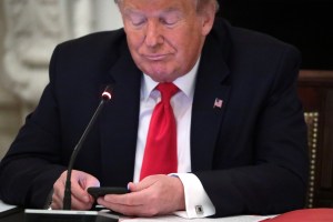 U.S. President Donald Trump looks at his phone during a roundtable at the State Dining Room of the White House June 18, 2020 in Washington, DC.