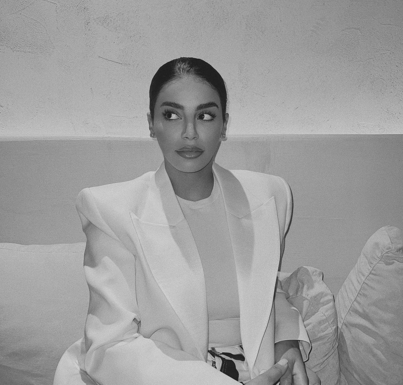 Black and white portrait of a woman dressed in a suit with shoulder pads, facing to the side of the camera.