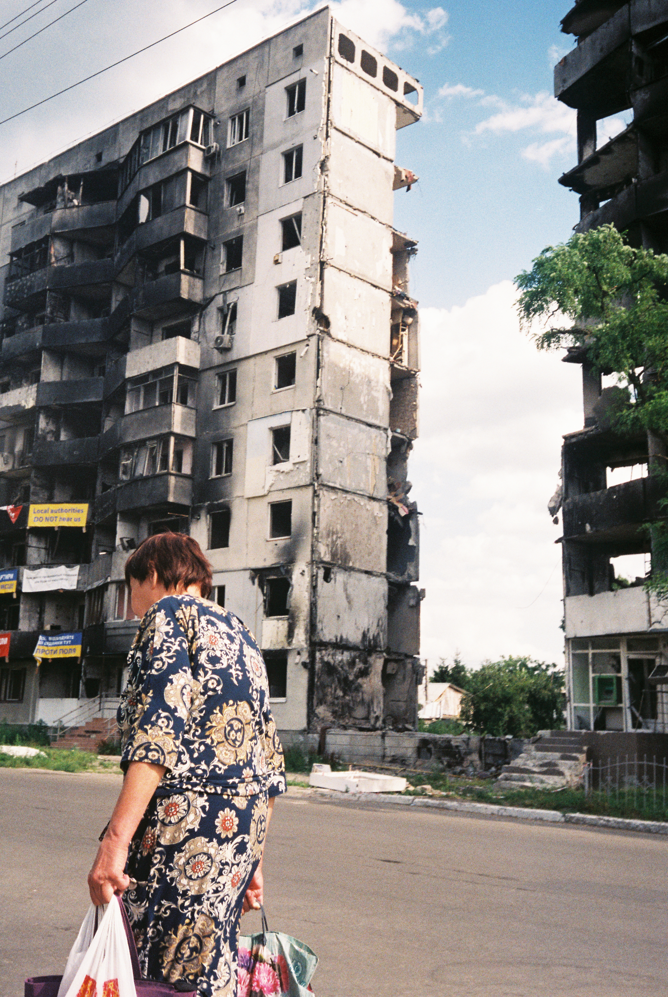 A woman carries shopping past a bombed-out building.