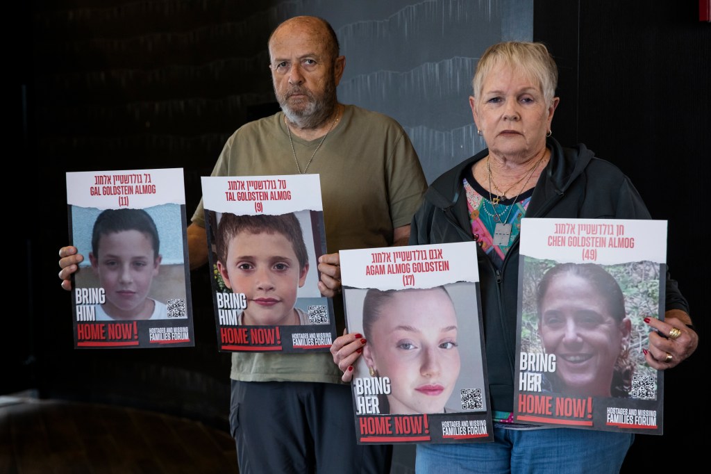 David and Varda Goldstein pose for a picture whilst holding-up photos of their 3 grandchildren, Gal, Tal and Agam, and their mother, Chen, who were kidnapped on Oct 7th deadly Hamas attack as they await more details on the hostages deal in a hotel on Nove