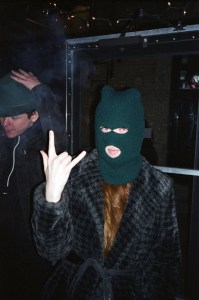 Woman in balaclava making hand gesture