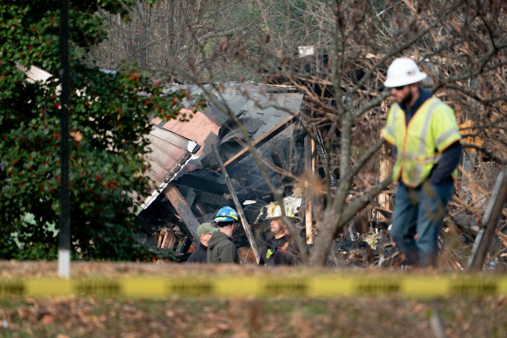 Workers look at a home that exploded in Arlington, Virginia, on December 4 and rocked a neighborhood with a powerful blast, on December 5, 2023.