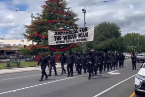 ​A group of men dressed in all black, wearing balaclavas, and carrying s sign reading "Australia is for the white man" in Ballarat on the weekend. [Image via Twitter]