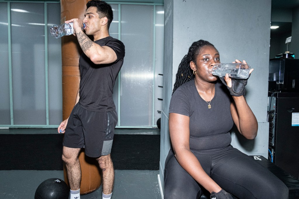 Two people in a gym drinking water