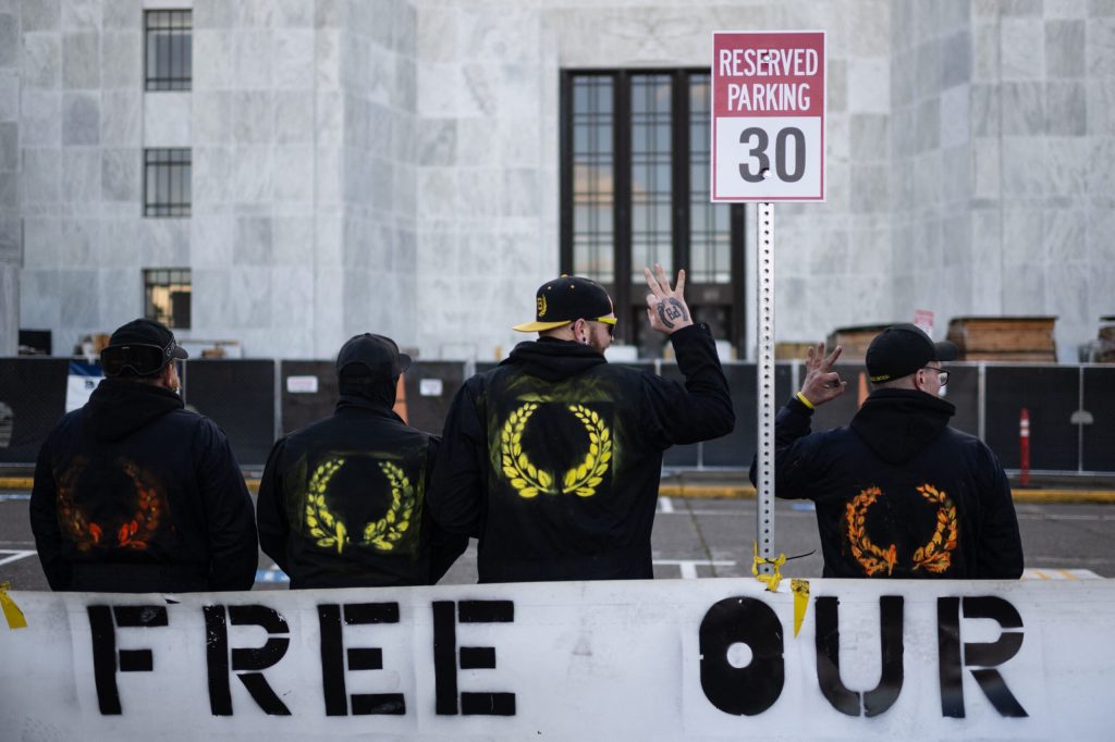 Members of the Proud Boys make the "OK" sign with their hands as they pose for a picture in front of the Oregon State Capitol building during a far-right rally on January 8, 2022 in Salem, Oregon. (