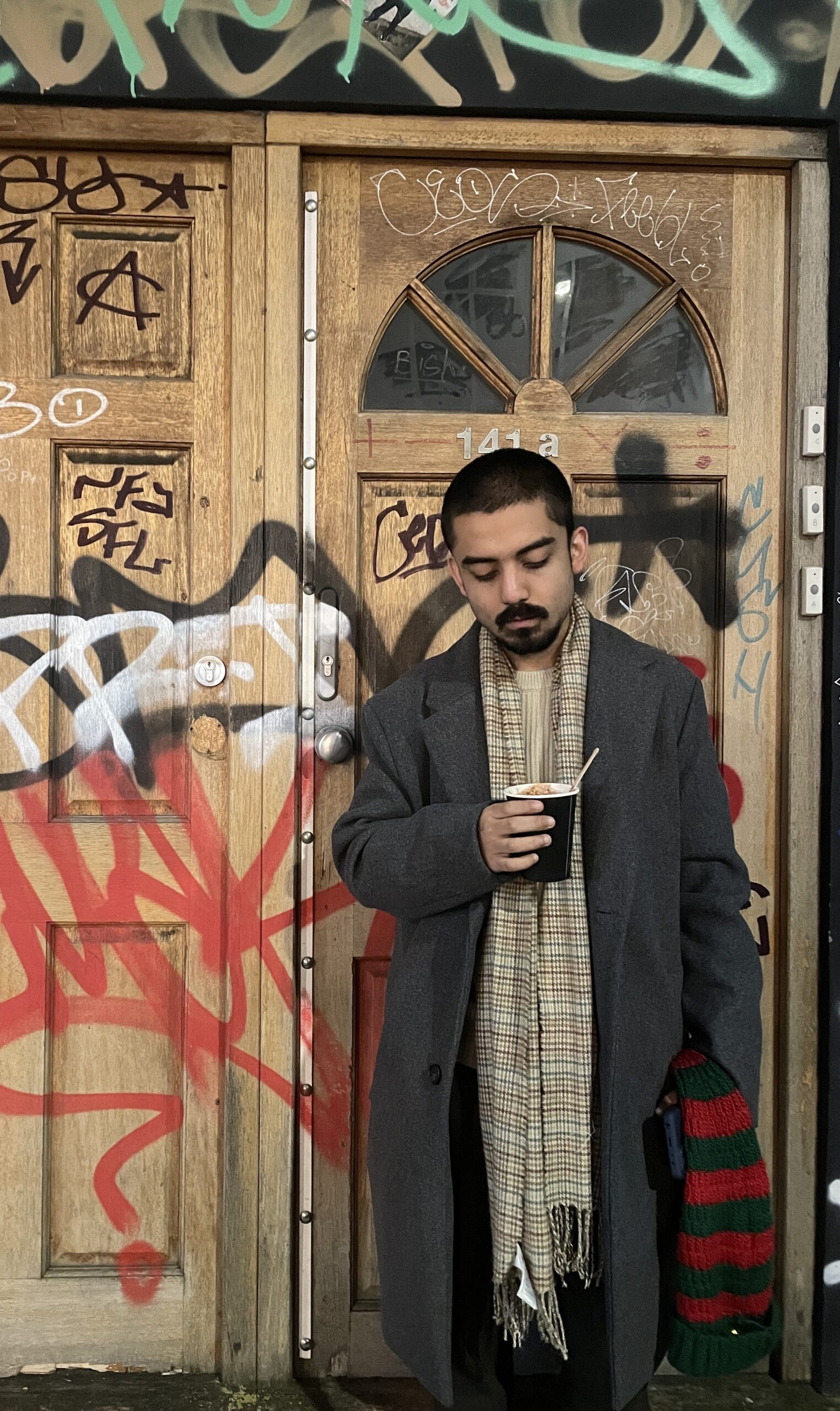 Young South Asian man holding cup of coffee