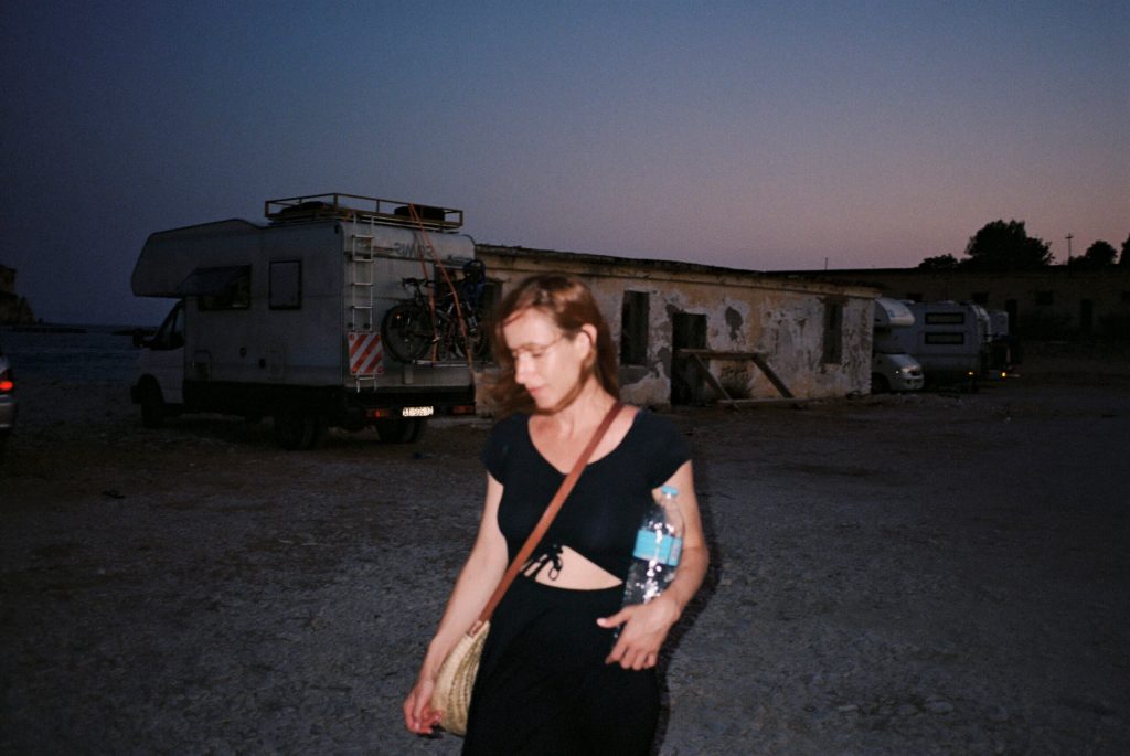 Woman in black outfit on beach next to trailers