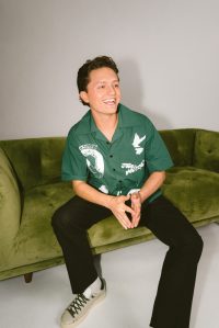 Connor Wood aka fibulaa on tiktok sits while laughing on a green couch