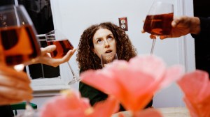 A woman drinking red wine surrounded by people