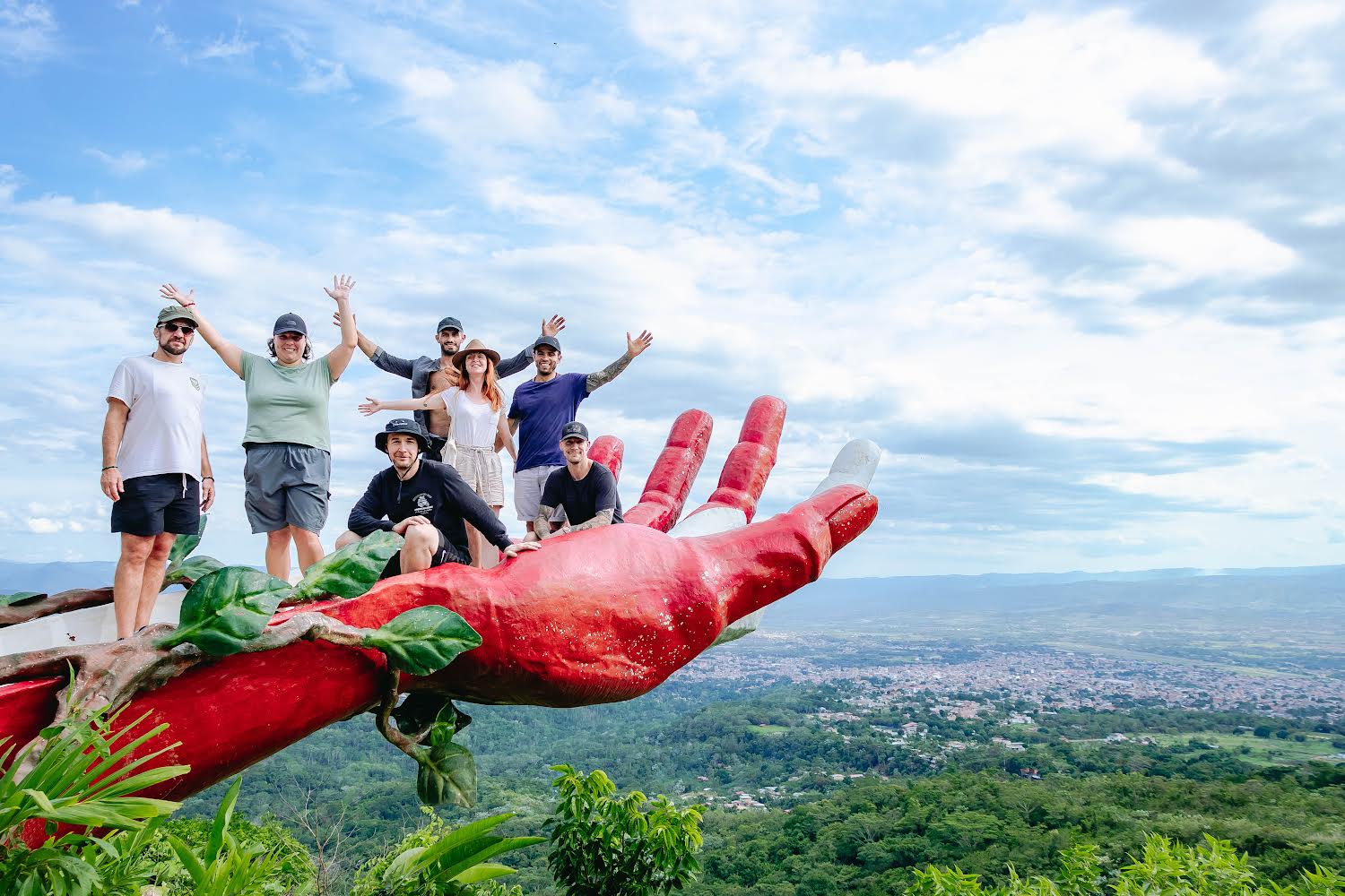 A group of military and emergency service veterans pose for a photo on a large hand statue, on a retreat in Peru.