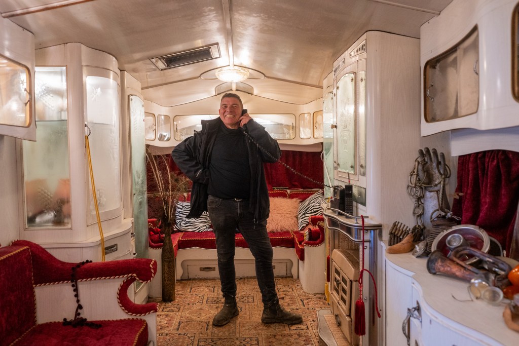 A man stands in the centre of his self-built home talking on the phone.