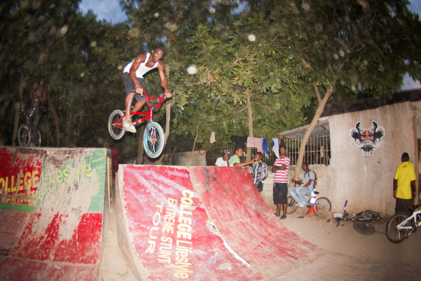 A man rides a red BMX bike down a red ramp.