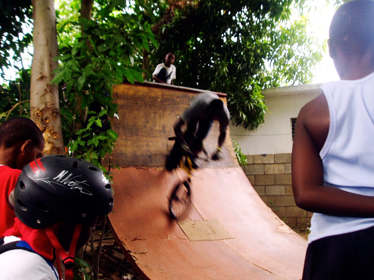 The blurred image of a man riding a BMX bike down a wooden ramp at high speed.