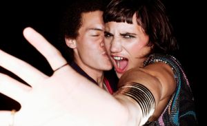 Man kissing woman who is holding her hand up to block the camera