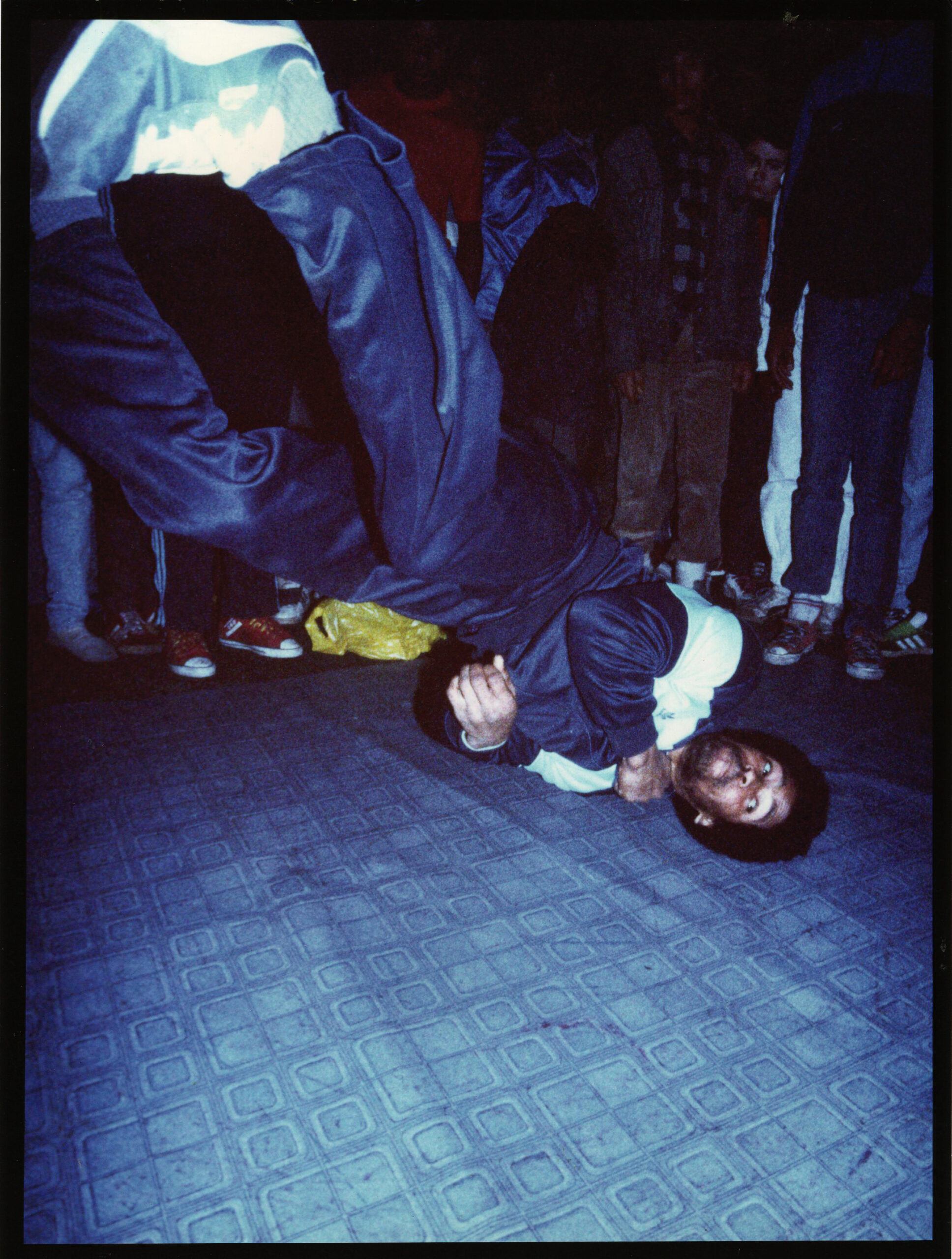 A professional dancer spins on his head with his feet in the air.