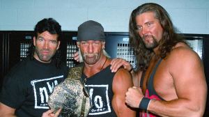 Three wrestlers pose for a photo holding a champion's belt.