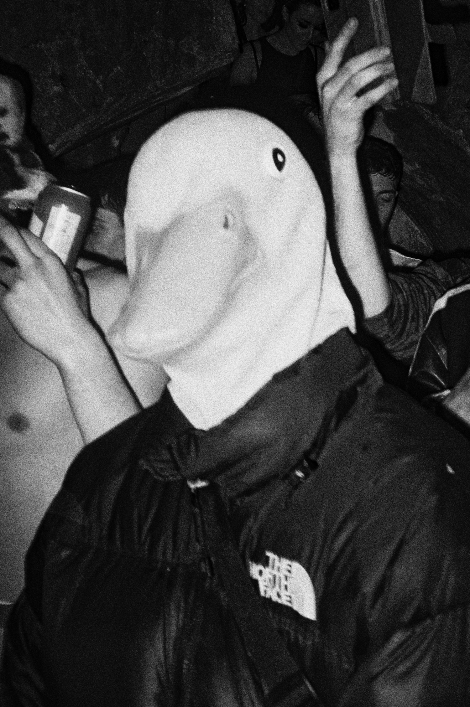 A person wearing a duck mask stares at the camera in the middle of a rave