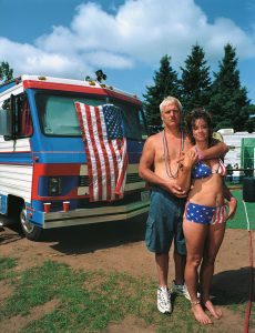 swingers in front of an RV with american flag and patriotic bathing suit and cargo shorts