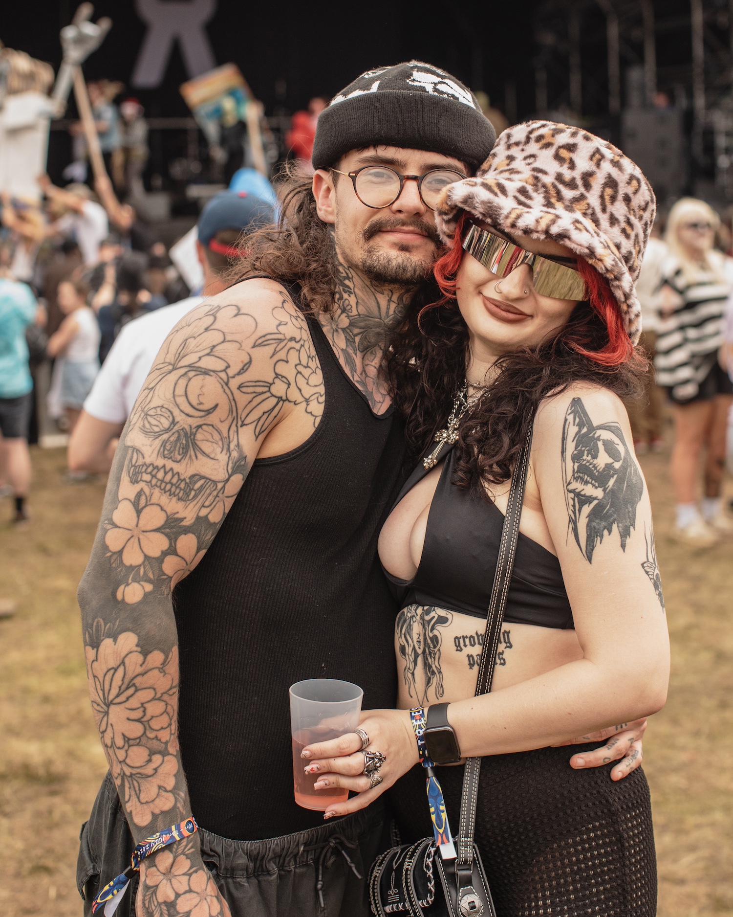 Two people with tattoos and vest tops at a festival