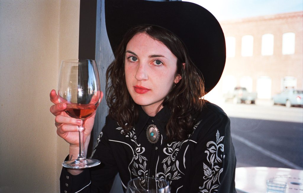 woman in a cowboy hat drinking a glass of wine