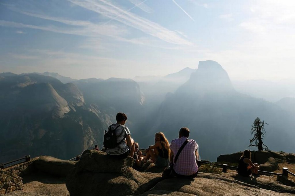 Visitors enjoy a hazy view of Half Dome from Glacier Point at Yosemite National Park.