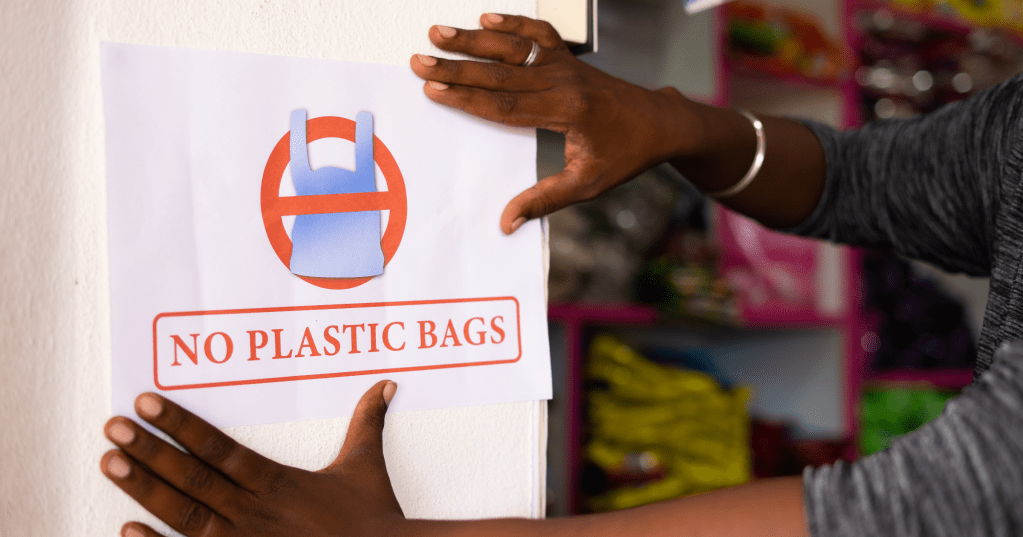 woman hanging a no plastic bags sign