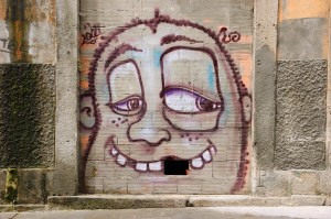 PORTO, PORTUGAL - APRIL 26, 2015: Funny face with mussing tooth (missing brick in the wall). Graffiti artist Costah uses a particular features of locations to create his cartoon style images.; Shutterstock ID 282311993; purchase_order: vice.com; job: ; client: ; other: