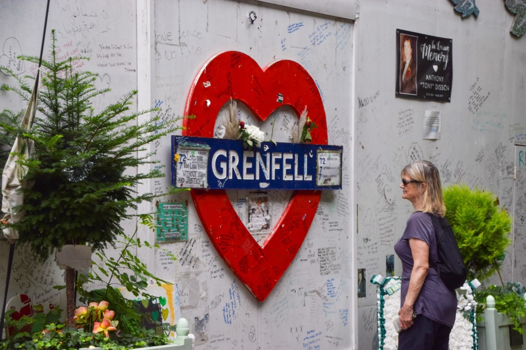 A woman looks at the tributes on the memorial wall next to Grenfell Tower. Photo by Vuk Valcic/ZUMA Press Wire/Shutterstock