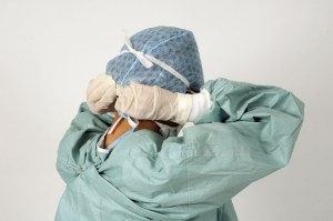 us healthcare system report Surgeon tying her mask onto her face